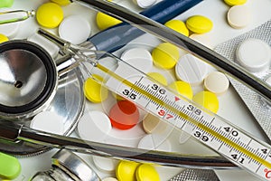 Doctor office desk with blisters of pills and clinical thermometer with stethoscope