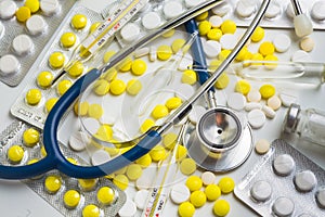 Doctor office desk with blisters of pills and clinical thermometer with stethoscope