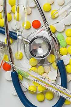 Doctor office desk with blisters of pills and clinical thermometer with stethoscope