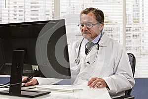 Doctor in office using computer, horizontal