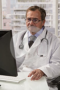 Doctor in office using computer, vertical