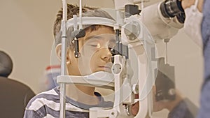 Doctor optometrist checks little boy's eyesight. Child in ophthalmologist room.
