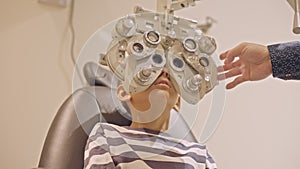 Doctor optometrist checks little boy's eyesight. Child in ophthalmologist room.