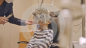 Doctor optometrist checks little boy's eyesight. Child in ophthalmologist room.