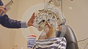 Doctor optometrist checks little boy's eyesight. Child in ophthalmologist room.