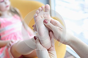 Doctor orthopedist examining feet of little girl closeup