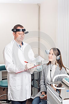 Doctor otolaryngologist examined the patient`s. diagnosis of hearing a special apparatus with headphones.