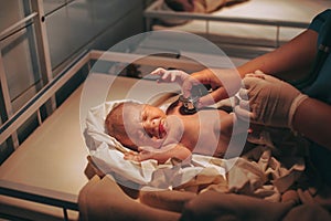 Doctor paediatrician examining baby in clinic, newborn baby crying in bed