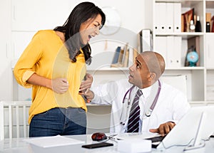 Doctor palpating abdomen of female patient in medical office