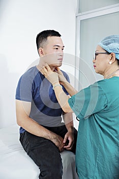 Doctor palpating neck of man