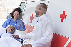 Doctor and paramedic wheeling in a elderly patient on a stretcher in front of an ambulance