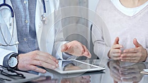 Doctor and patient conversation with tablet computer in clinic office. Medicine and Health care