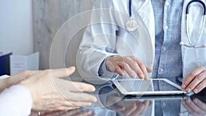 Doctor and patient conversation with tablet computer in clinic office. Medicine and Health care