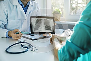Doctor and patient discuss chest x-ray results on digital tablet in clinics office