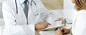 Doctor and patient discussing medical exam results while sitting at the desk in clinic, close-up. Male physician using