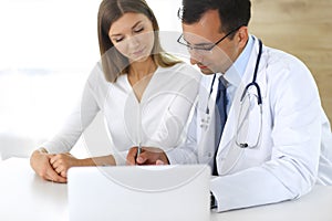 Doctor and patient discussing the results of a physical examination while sitting at a desk in a clinic. A male doctor