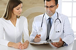 Doctor and patient discussing the results of a physical examination while sitting at a desk in a clinic. A male doctor