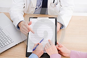 Doctor and patient are discussing something, hands at the table