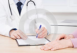 Doctor and patient are discussing something, just hands at the table, medical insurance.