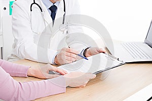 Doctor and patient are discussing something, just hands at the table, medical insurance.