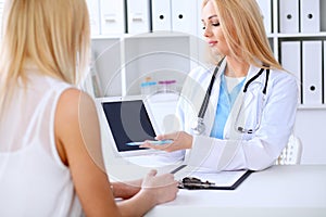 Doctor and patient discussing something while phisician pointing into laptop computer
