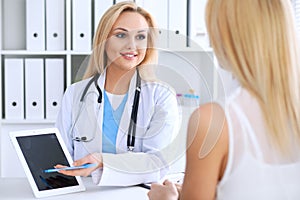 Doctor and patient discussing something while phisician pointing into laptop computer