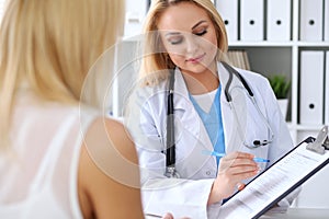 Doctor and patient discussing something while physician pointing into medical history form at clipboard