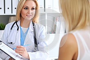 Doctor and patient discussing something while physician pointing into medical history form at clipboard