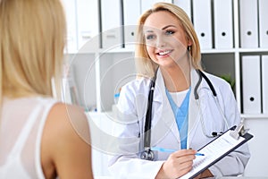 Doctor and patient discussing something while physician pointing into medical history form at clipboard