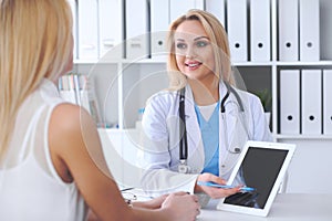 Doctor and patient discussing something while physician pointing into touch pad computer