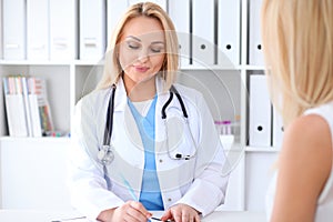 Doctor and patient discussing something while sitting at the table at hospital. Medicine and health care concept