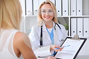 Doctor and patient discussing something while sitting at the table at hospital. Medicine and health care concept