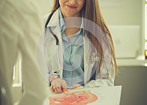 Doctor and patient discussing something while sitting at the table . Medicine and health care concept