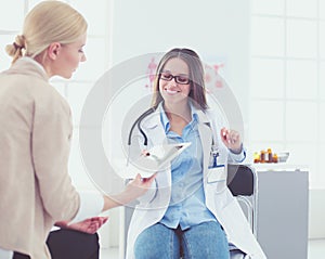 Doctor and patient discussing something while sitting at the table . Medicine and health care concept