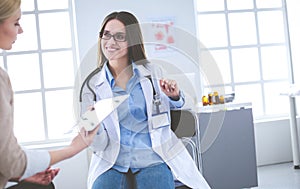 Doctor and patient discussing something while sitting at the table . Medicine and health care concept