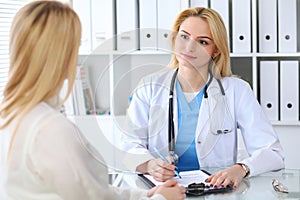 Doctor and patient discussing something while sitting at the table . Medicine and health care concept