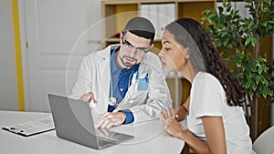 Doctor and patient engrossed in serious conversation using laptop at clinic