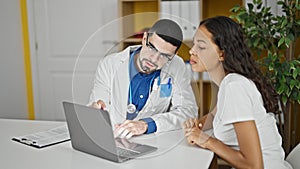 Doctor and patient engrossed in serious conversation using laptop at clinic