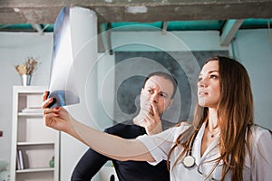 Doctor and patient examine head roentgen at clinic