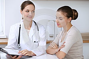 Doctor and patient having a pleasure talk while sitting at the desk at hospital office. Healthcare and medicine concept