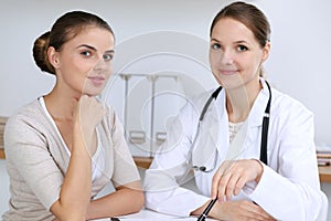 Doctor and patient having a pleasure talk while sitting at the desk at hospital office. Healthcare and medicine concept