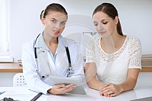 Doctor and patient having a pleasure talk while sitting at the desk at hospital office. Healthcare and medicine concept