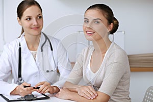 Doctor and patient having a pleasure talk while sitting at the desk at hospital office. Healthcare and medicine concept