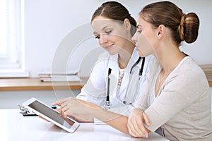 Doctor and patient having a pleasure talk while sitting at the desk at hospital office. Healthcare and medicine concept