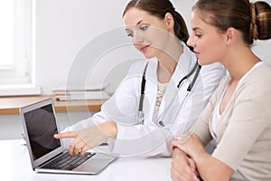 Doctor and patient having a pleasure talk while sitting at the desk at hospital office. Healthcare and medicine concept