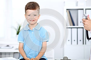 Doctor and patient in hospital. Happy little boy having fun while being examined with stethoscope. Healthcare and