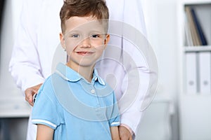 Doctor and patient in hospital. Happy little boy having fun while being examined with stethoscope. Healthcare and