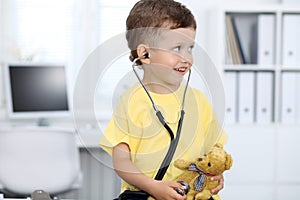 Doctor and patient in hospital. Happy little boy having fun while being examined with stethoscope. Healthcare and
