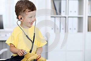 Doctor and patient in hospital. Happy little boy having fun while being examined with stethoscope. Healthcare and