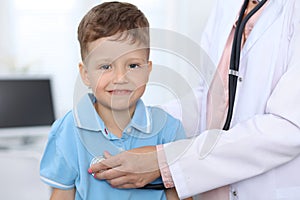 Doctor and patient in hospital. Happy little boy having fun while being examined with stethoscope. Healthcare and